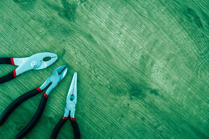 three black handled pliers on brown surface